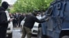 Un bărbat mascat scrie cu spray litera "Z" pe un vehicul al forțelor de securitate în timpul protestelor din Zvecan, în nordul Kosovo, pe 29 mai. 