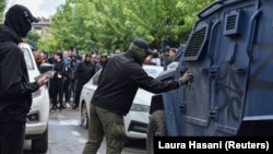 Egy maszkos férfi Z betűt fúj a biztonsági erők egyik járművére május 29-én az észak-koszovói Zvečanban tartott tüntetések során
