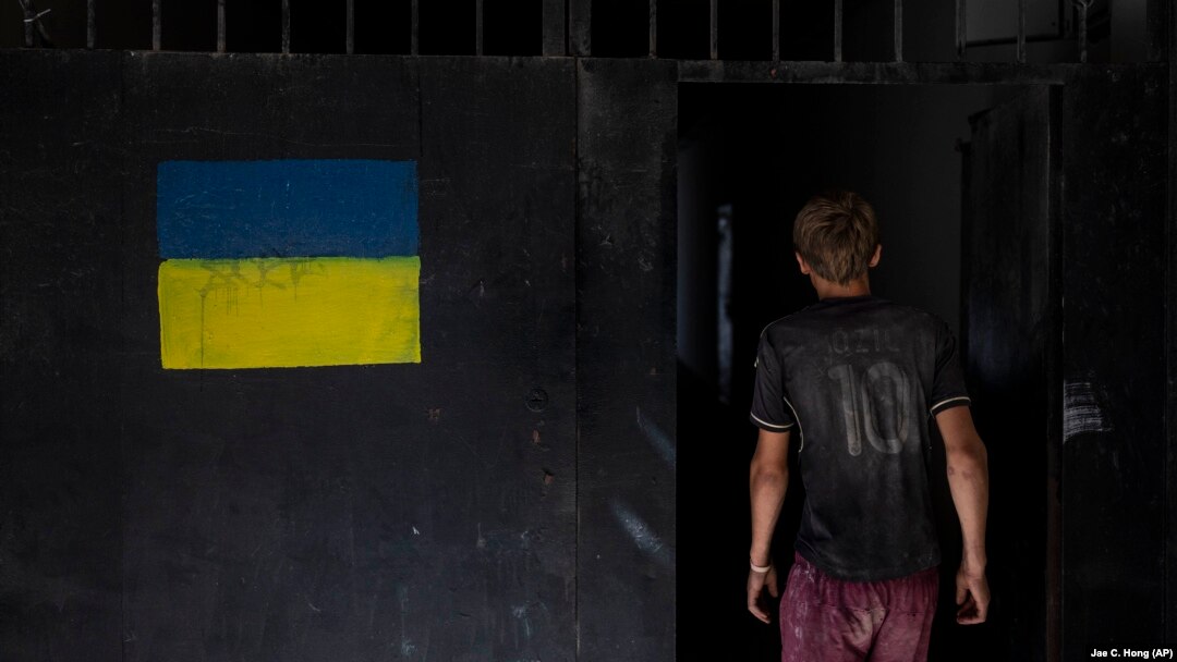 Украинанын желегинин сүрөтү түшүрүлгөн дубалдын жанында бараткан бала. Одессада тартылган сүрөт. 
