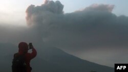 Индонезийската планина Марапи изхвърля вулканична пепел, докато човек снима гледката от село Ласи, Западна Суматра. Стотици спасители се впуснаха в акция по намирането на дузина туристи в понеделник, изчезнали след изригване на вулкан, при което загинаха поне 11 души.