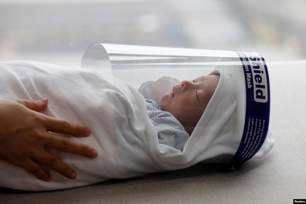 Foshnja e porsalindur Phuc An, e veshur me një maskë mbrojtëse për fytyrën, shihet përpara se të largohej nga shtëpia për vaksinimin e tij.