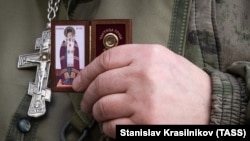 Российский полковой священник с иконой в руке в зоне боевых действий