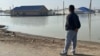 Житель 4-го аула города Кульсары Нурмухан Байжанов издалека наблюдет за своим затопленным домом. Атырауская область, 10 апреля 2024 года