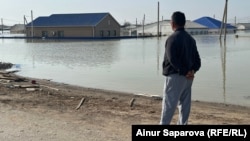 Житель 4-го аула города Кульсары Нурмухан Байжанов издалека наблюдет за своим затопленным домом. Атырауская область, 10 апреля 2024 года