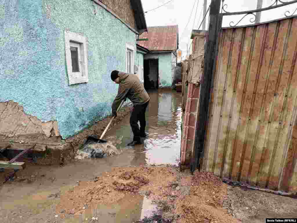  Мужчина пытается отвести воду, подступающую к дому жительницы Коянды Аягоз Тугеловой. 27 марта 2024 года 
