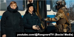 Росгвардеец на блокпосту на окуппированной территории Украины обыскивает пассажиров автобуса, февраль 2023 года