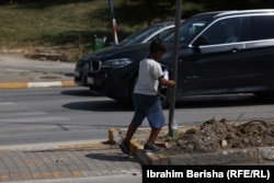 Egy fiatal fiú pénzt koldul, amiért cserébe autóablakot tisztít Pristina utcáin