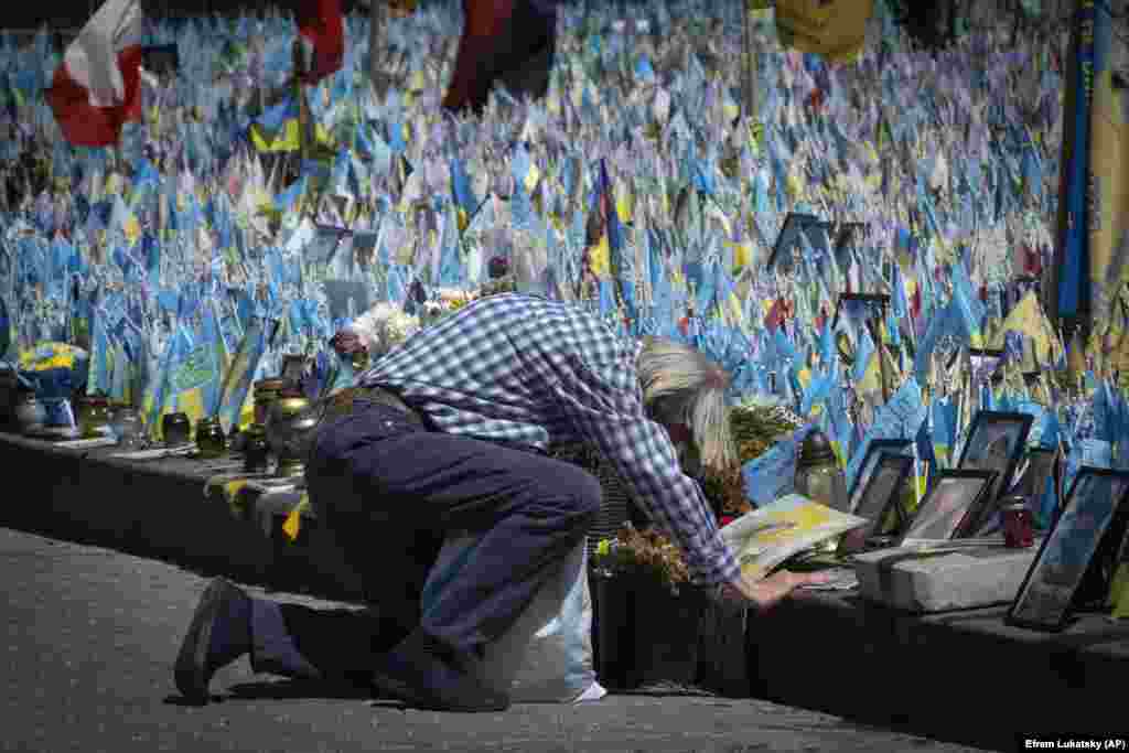 Një burrë duke u gjunjëzuar para një memoriali të improvizuar për ushtarët e rënë ukrainas, në Sheshin e Pavarësisë, në Kiev, Ukrainë, më 23 korrik. Secili flamur i sjellë nga të afërmit mban emrin e një ushtari të vrarë në luftime me trupat ruse.