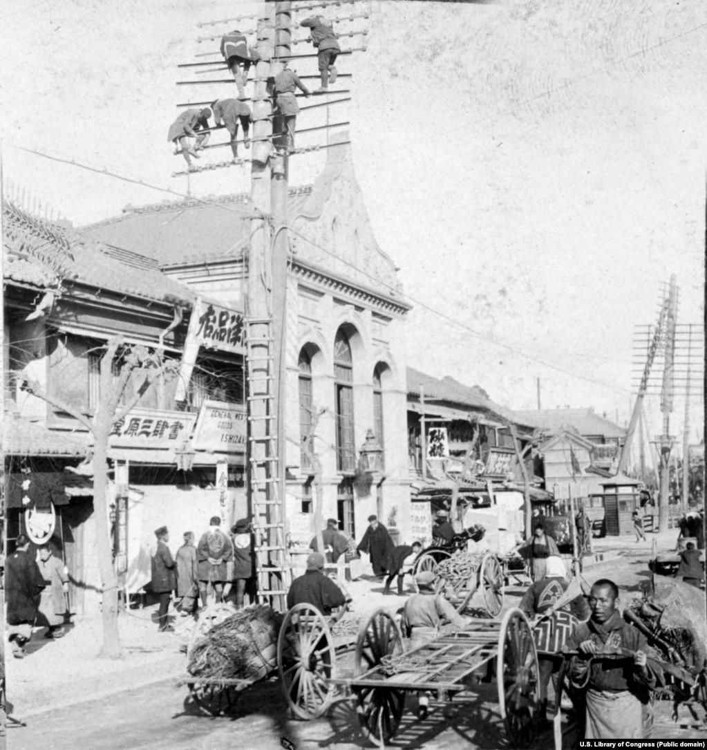 Punëtorët duke ndërtuar shtylla telegrafi mbi një rrugë të ngarkuar në Tokio më 1905.