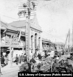 Рабочие устанавливают телеграфные столбы над оживленной улицей Токио, 1905 год