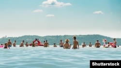 Njerëzit duke u larë në ujërat e liqenit Balaton, Hungari, në një ditë vere më 2023.