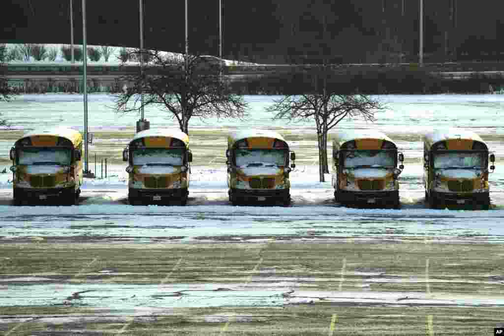 Autobusët e shkollave, të mbuluar me borë, në një parking në Aeroportin Ndërkombëtar O&#39;Hare në Çikago, të dielën, 14 janar 2024. Paralajmërimi për motin e ftohtë dhe me erë është në fuqi në zonën e Çikagos, ndërsa kushtet vazhdojnë të jenë të rrezikshme.