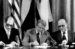 Egipatski predsjednik Anvar Sadat (lijevo), američki predsjednik Jimmy Carter (u sredini) i premijer Izraela Manahem Begin potpisuju jedan od dva sporazuma sklopljena u Canm Davidu, 17. septembar 1978.