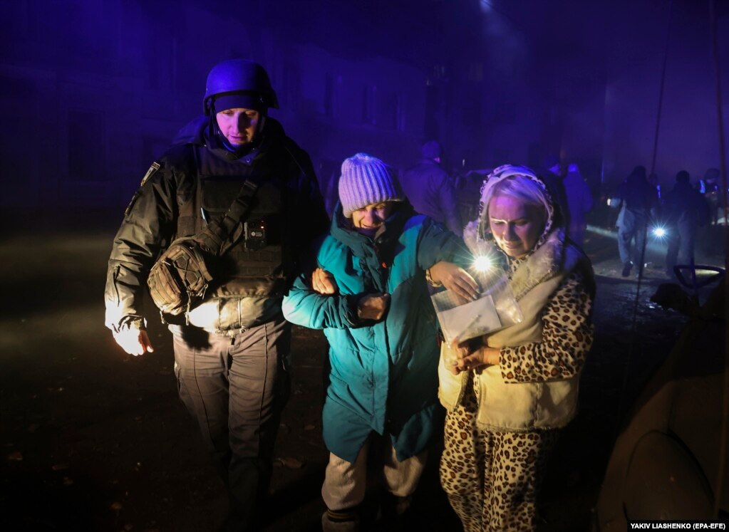 Një oficer policie duke ndihmuar dy gra pranë vendit ku ndodhi sulmi me raketa në Harkiv. Kryetari i bashkisë së qytetit tha se disa ndërtesa banimi u shkatërruan dhe se nuk kishte objektiva ushtarakë në zonë.  