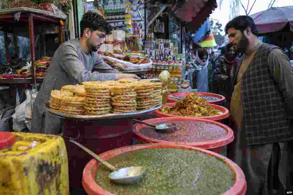 Një shitës ëmbëlsirash në një treg në Kabul më 22 mars 2023. Njerëzit blejnë artikuj ushqimorë si përgatitje për Ramazan.