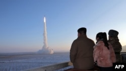 Ova nedatirana slika koju je objavila agencija KCNA Sjeverne Koreje 19. decembra 2023. prikazuje predsjednika Kim Jong-una (lijevo) i njegovu kćer kako gledaju probno lansiranje interkontinentalne balističke rakete Hwasongpho-18 (ICBM) ) na neotkrivenoj lokaciji