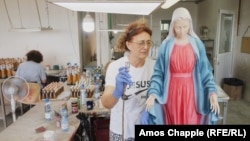 Egy nő Szűz Mária-szobrot fest egy műhelyben Međugorje külvárosában