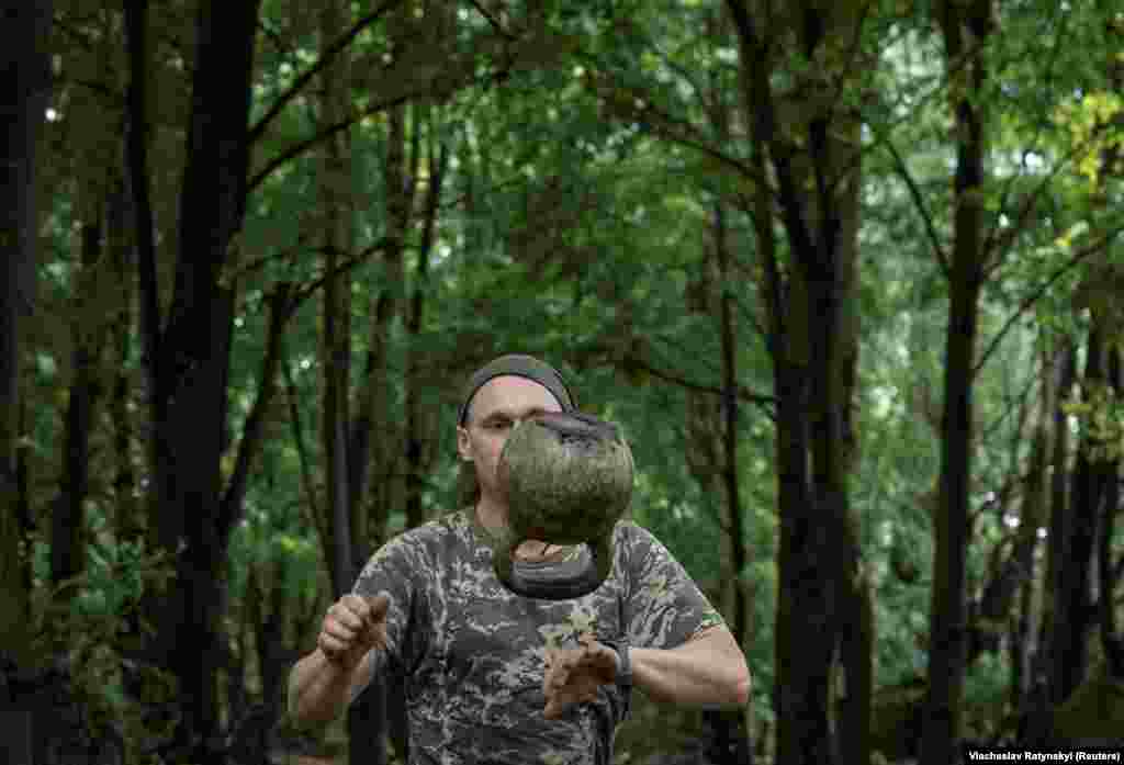 Një artiljer ukrainas duke ushtruar me një peshë me dorezë (kettlebell)&nbsp;pranë vijës së frontit në rajonin Harkiv të Ukrainës.