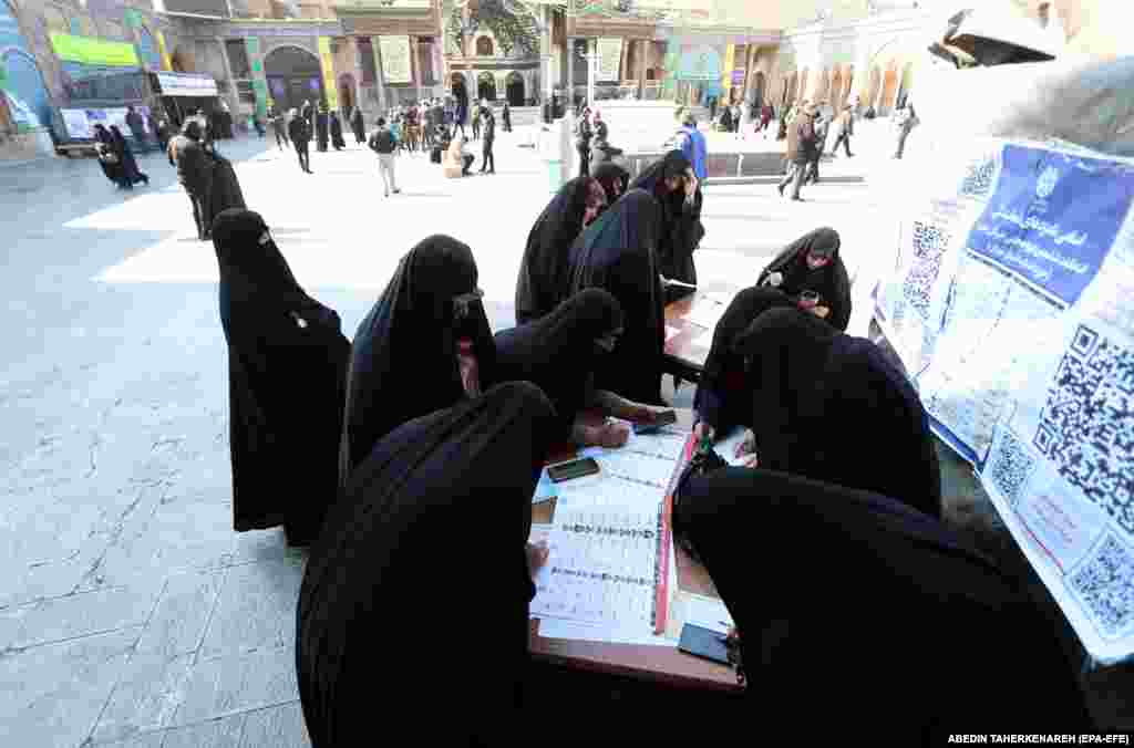 Veiled Iranian women fill out their ballot papers during the elections at the Abdol-Azim shrine in Shahre-Ray, southern Tehran, pn March 1.