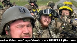 Members of the Russian Volunteer Corps pose for a picture atop an armored vehicle at a border crossing in Kozinka, Belgorod region, Russia, in this handout picture released on May 23.