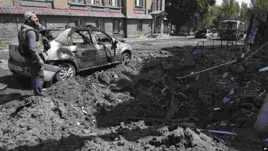 An investigator examines the site, after shelling that Russian-installed officials in Donetsk said was by Ukrainian forces.