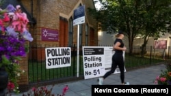 Žena trči pored glasačkog mesta u Londonu ubrzo pošto su otvorena birališta na izborima u Velikoj Britaniji, 4. jul 2024.