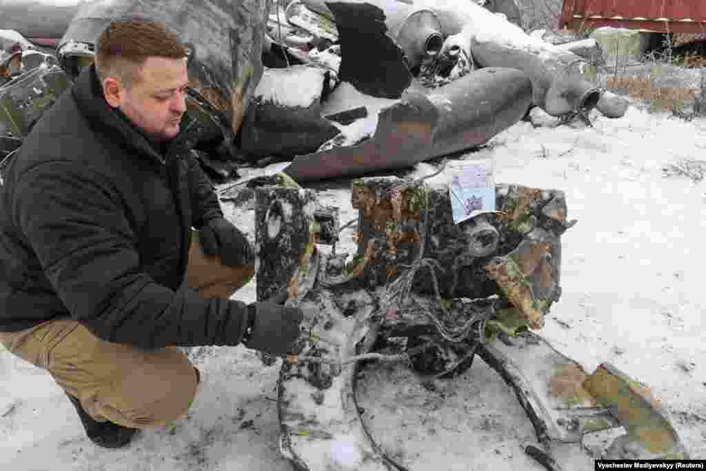 Dmytro Chubenko from Kharkiv&#39;s prosecutor&#39;s office kneels alongside a fragment of a ballistic missile that Ukraine believes was built in North Korea, supplied to Russia, and launched into Ukraine. Ukrainian presidential adviser Mykhaylo Podolyak on January 5 joined the United States in saying that Russia has hit Ukraine with missiles supplied by North Korea for the first time since launching its full-scale invasion. Russia &quot;is attacking Ukrainians with missiles received from a state where citizens are tortured in concentration camps for having an unregistered radio, talking to a tourist, watching TV shows,&quot; Podolyak said on X, formerly Twitter.
