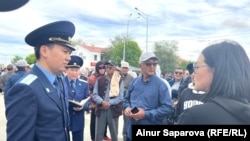 Прибывший из Атырау работник прокуратуры разговаривает с кульсаринцами, стоящими на городской площади. 15 мая 2024 года