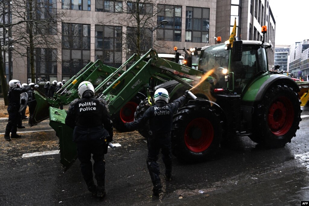 Një oficer policie përdor sprej kundër fermerëve protestues në Bruksel më 26 shkurt 2024.