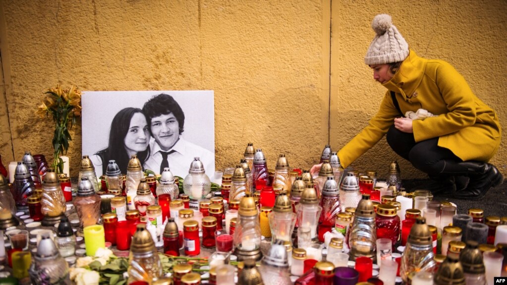 A woman places candles in front of the portraits of the murdered Jan Kuciak and his fiancee Martina Kushnirova.  The photo is from 2018.