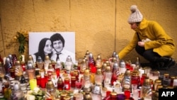 Жена полага свещи пред портретите на убитите Ян Куциaк и годеницата му Мартина Кушнирова. Снимката е от 2018 г.