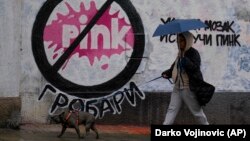 Žena sa psom šeta pored murala koji potpisuju navijači kluba Partizan. Beograd, 12. maj 2023.