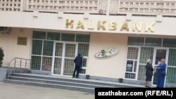 Turkmenistan. Two women talk and one man withdraws money from ATM in front of the one of the branches of Halkbank in Ashgabat. ATMs, bank.