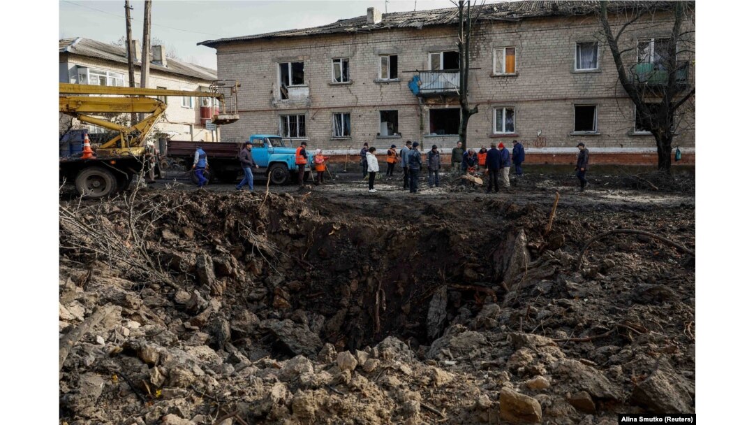 Residents stand near a crater caused by a Russian missile strike in the town of Selydove, Donetsk region, on November 15.