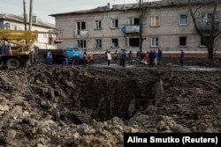 Residents stand near a crater caused by a Russian missile strike in the town of Selydove, Donetsk region, on November 15.