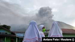 Učenice lokalne škole posmatraju vulkan Mount Marapi dok izbacuje pepeo, Agamo, provincija Zapadna Sumatra, Indonezija, 4. decembra 2023.