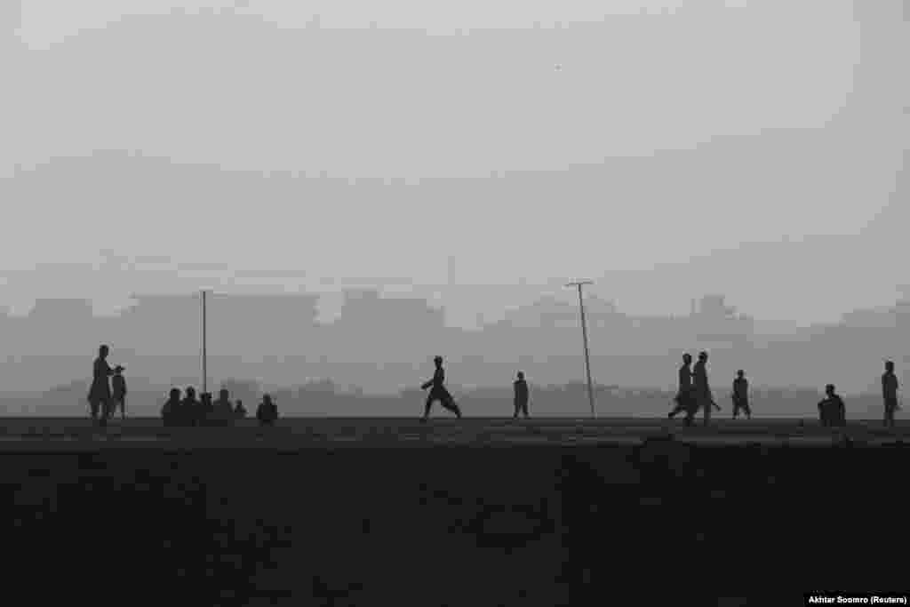 Siluetat e fëmijëve teksa luajnë kriket mes mjegullës në Karaçi, Pakistan.