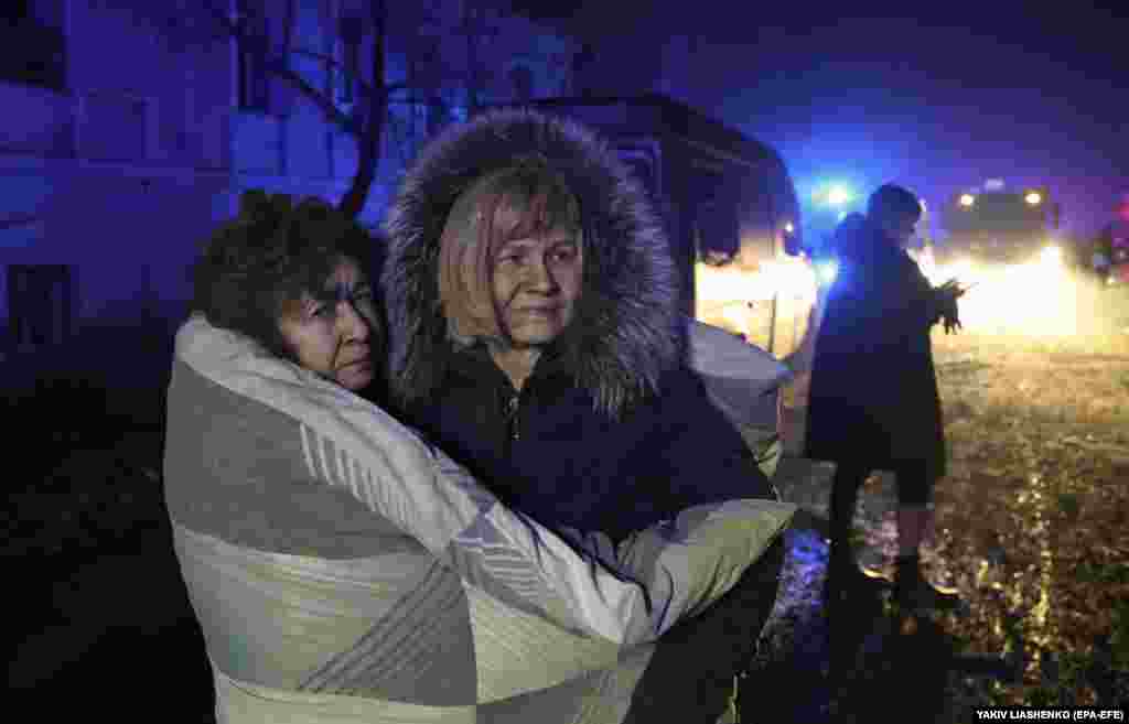 Locals huddle together in the freezing temperatures as they watch rescuers at work. &nbsp;