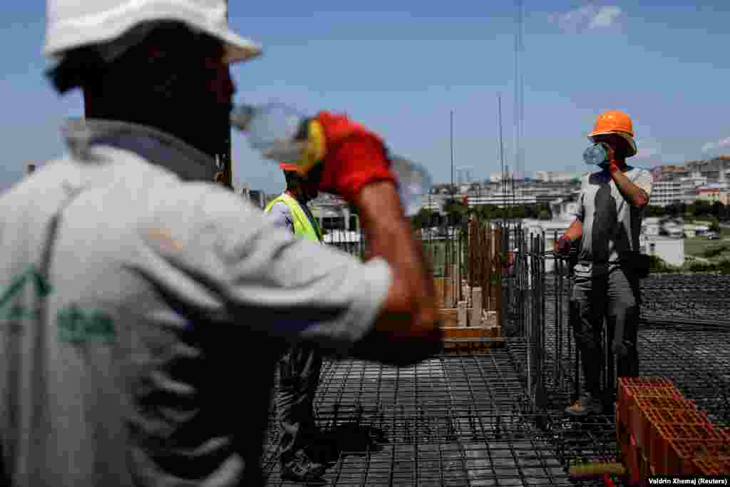 Građevinski radnici piju vodu dok rade na zgradi u Prištini.