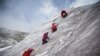 Katër alpiniste të veshura me funde të kuqe përdorin sëpatat e akullit për t&#39;u ngjitur në malin e mbuluar me borë Huayna Potosi, afër El Altos, Bolivi, 28 shkurt 2024.