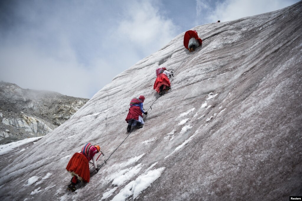 Katër alpiniste të veshura me funde të kuqe përdorin sëpatat e akullit për t&#39;u ngjitur në malin e mbuluar me borë Huayna Potosi, afër El Altos, Bolivi, 28 shkurt 2024.