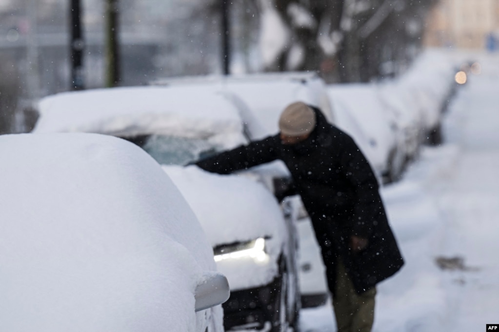 Një burrë duke larguar borën nga vetura e tij në Sundbyberg, afër Stokholmit, më 4 janar 2024.