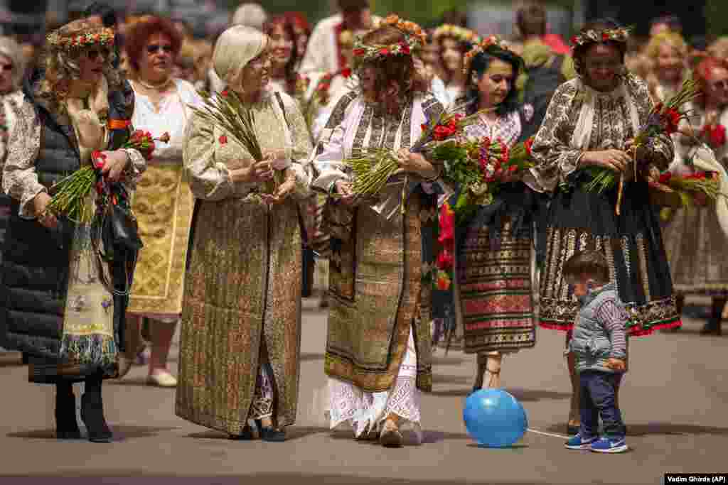 A young boy drops his balloon as women wearing traditional Romanian costumes walk during an event celebrating the country&#39;s rural national outfits in Bucharest.&nbsp;