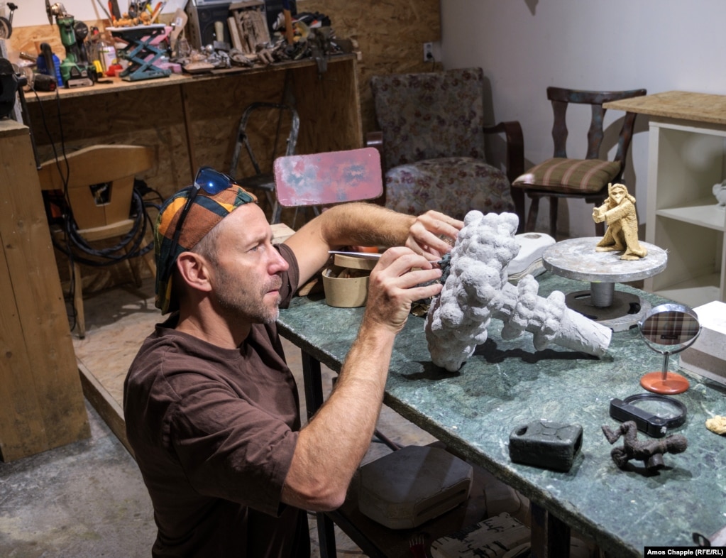 Mihaly Kolodko në studion e tij në Budapest, më 11 korrik. Skulptori po punon në një mini-statujë të Vladimir Putinit duke bërë engjëj dëbore mbi një re kërpudhe bërthamore.