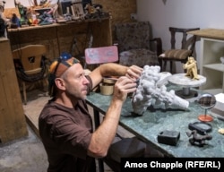 Михайло Колодко у своїй майстерні в Будапешті 11 липня. Скульптор працює над міні-статуеткою Володимира Путіна, який створює снігових янголів на вершині ядерної грибоподібної хмари