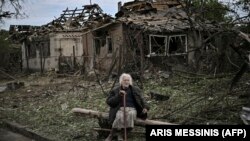 Літня жінка сидить перед зруйнованими будинками у місті Дружківка на Донеччині, 5 червня 2022 року