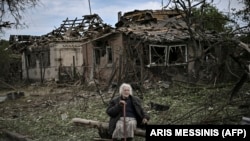 Një grua e moshuar shihet e ulur para shtëpive të shkatërruara si pasojë e një sulmi me raketë në qytetin Druzhkovka në rajonin lindor të Donbasit në Ukrainë.