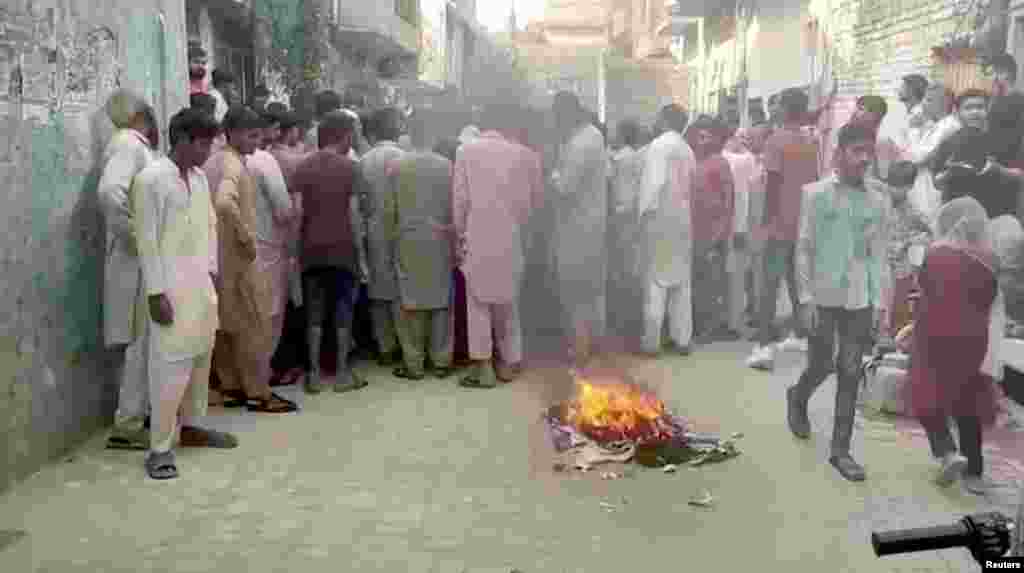 Protesters gather near objects set on fire on a street in Jaranwala.