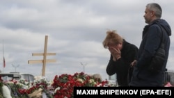Egy nő sír Moszkva mellett, a koncerttermi lövöldözés áldozatainak rögtönzött emlékművénél 2024. március 26-án