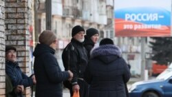 Місцеві жителі в окупованому Мелітополі Запорізької області поряд з банером «Росія – це розвиток», Україна, 13 лютого 2023 року